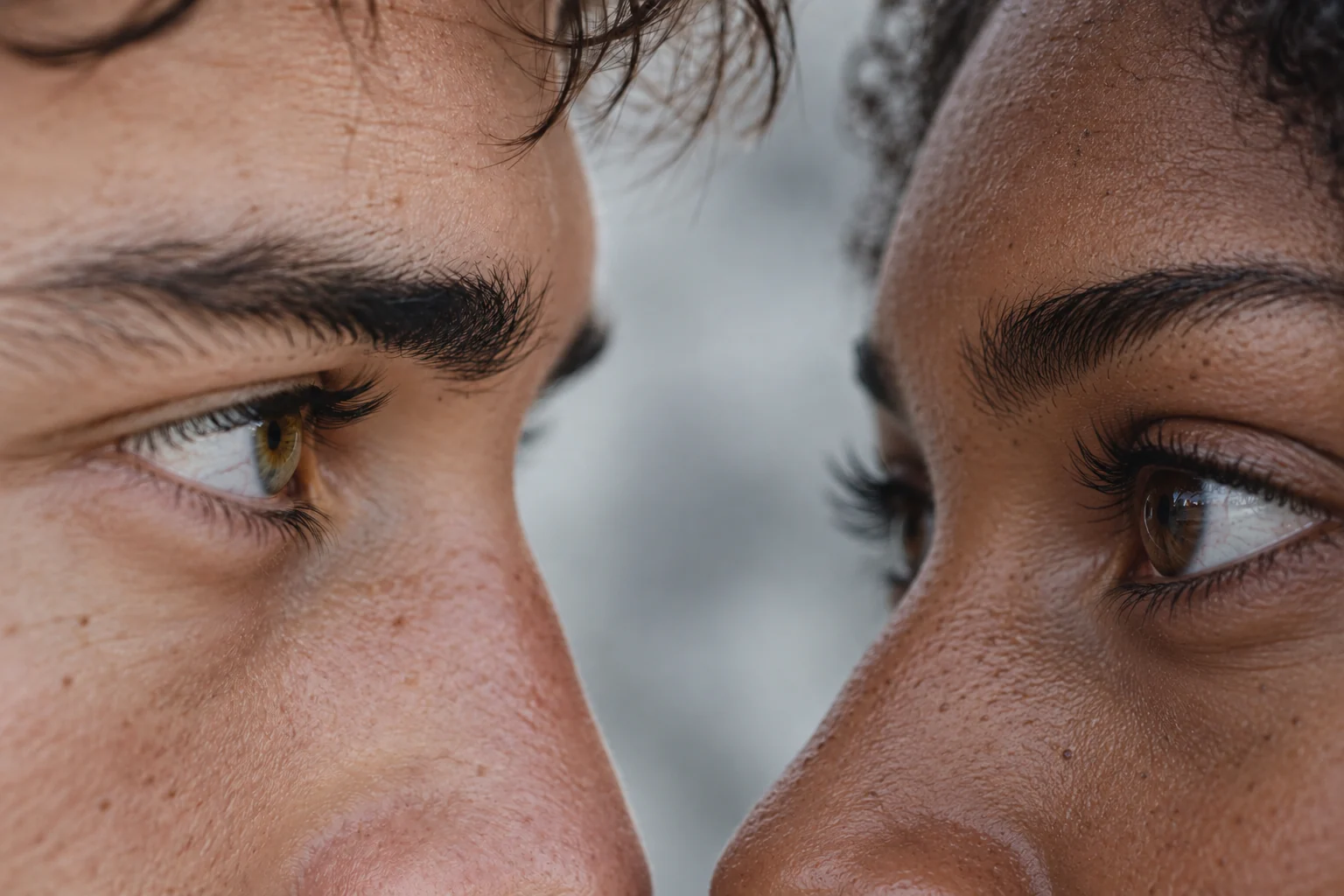 Primeiríssimo plano dos olhos e olhares de um casal, com uma mulher negra à direita