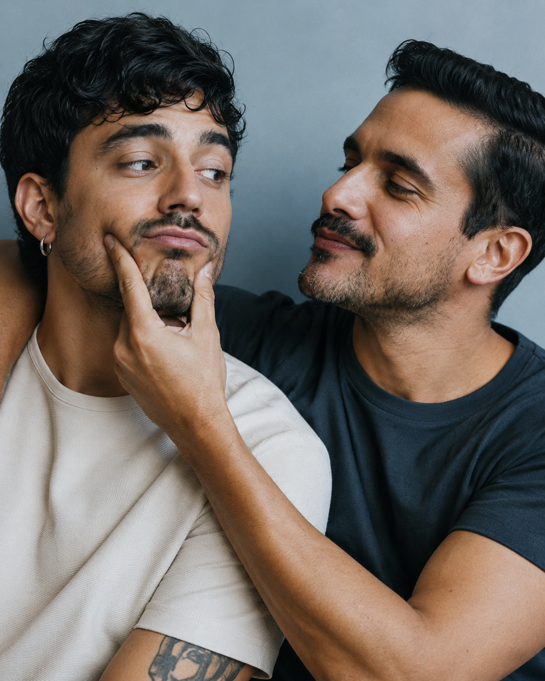 Casal formado por dois homens em retrato próximo, com gesto lúdico e cumplicidade